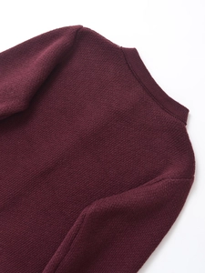 Detailed close-up of dark red knit sweater fabric showing texture and shoulder seams