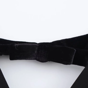 Detailed view of the velvet fabric texture and bow tie design on a black short dress