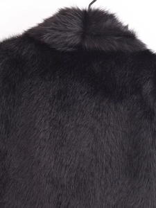 Gros plan d'un gilet en fausse fourrure noire montrant la texture dense et douce