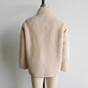 Detailed back view of a beige faux fur jacket with stylish contrast dark piping detail