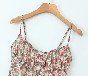 Detail of floral spaghetti strap top featuring red blossoms and white front buttons