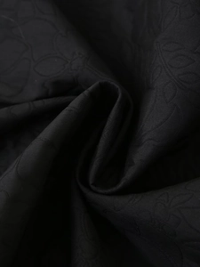 Close-up of black floral embossed fabric showing fine texture and satin sheen on jacket