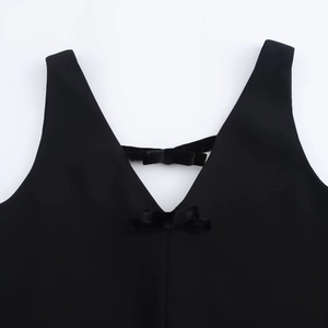 Detail of deep V-neck dress featuring velvet bows on a black sleeveless straight dress