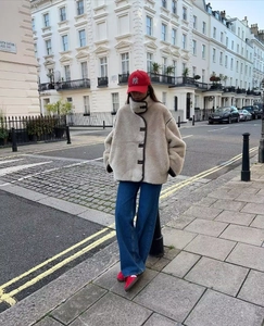 Oversized beige fleece jacket with dark trim styled with wide-leg jeans and sneakers