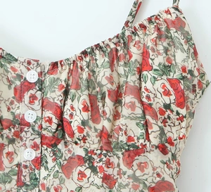 Detail of red floral print dress featuring front pleats and white button decorations