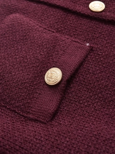 Macro shot of gold embossed crest buttons on burgundy knit fabric sweater