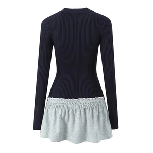 Detail view of navy ribbed knit bodice stitched with a grey flared hem on a slim dress