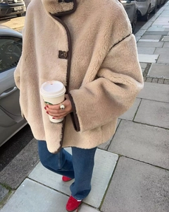 Detail of oatmeal faux fur jacket with brown suede trim and button closure design