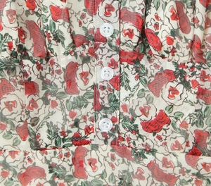 Close-up of red rose floral pattern and white translucent buttons on summer dress