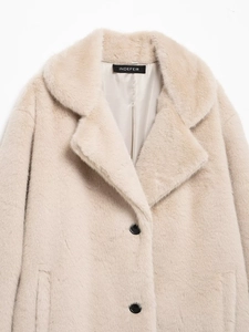 Detailed view of plush beige faux fur coat featuring wide lapels and black buttons