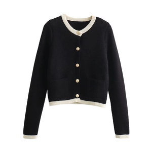 Detailed close-up of golden metal buttons on the black knit cardigan with white trim