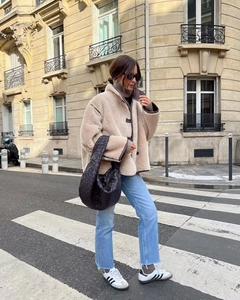 Chic women's winter street style with beige shearling jacket and woven leather handbag