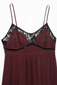 Détail d'une robe caraco bordeaux avec dentelle florale noire et texture plissée