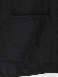 Close-up of black quilted jacket pocket featuring elegant floral embossing detail