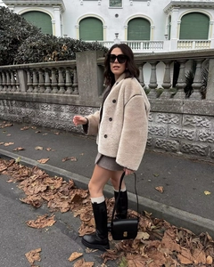 Faux fur beige cropped jacket paired with black knee-high boots in a street fashion look
