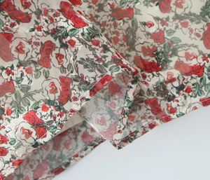 Close-up of floral print dress fabric featuring red roses and detailed neat stitching