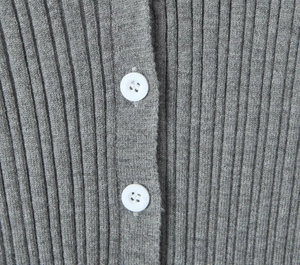 Detailed macro view of grey ribbed knit texture with white buttons on the cardigan