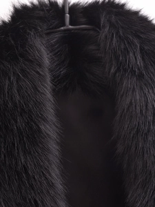 Gros plan du détail du col en fausse fourrure noire sur gilet d'hiver pour femme