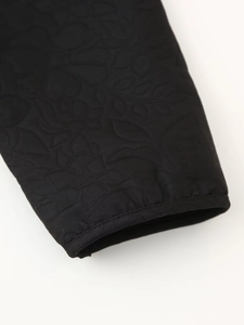 Close-up of sleeve cuff featuring detailed floral embroidery and quilted texture on black jacket