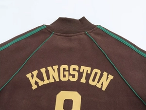 Dettaglio della stampa Kingston 8 su felpa marrone con colletto a righe verdi