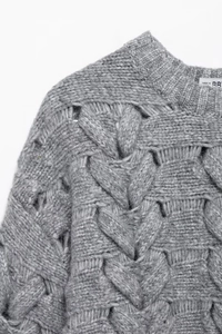 Gros plan sur un pull en maille grise avec torsades épaisses et détails ajourés élégants