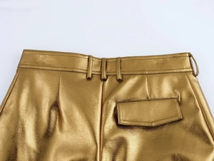 Gros plan sur pantalon cargo doré effet cuir avec texture grainée et poche à rabat