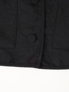 Close-up of black quilted jacket featuring floral embroidery textures and cloth buttons