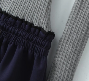 Detail of grey ribbed knit splicing with navy smocking and black wavy ruffle trim