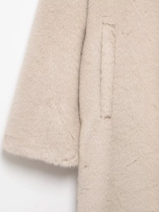 Detail of soft beige faux fur coat showing plush cuff and side pocket texture closeup