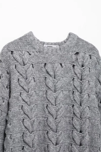 Détail d'un pull gris en maille torsadée avec motifs de cœurs et design ajouré chic