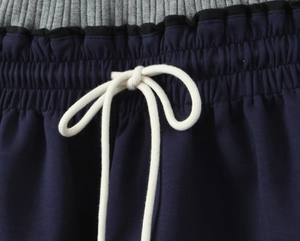 Macro detail of the tricolor ribbed waistband with white drawstring and ruffle trim