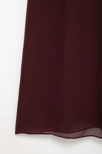 Détail de l'ourlet de robe en mousseline bordeaux montrant la couture précise et le tissu léger