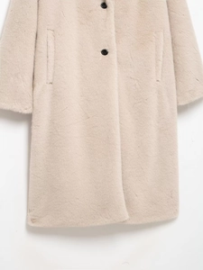 Detail view of cream faux fur coat showing black buttons and soft fabric texture