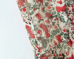 Detail of floral dress showing invisible side zipper and elastic smocked fabric texture