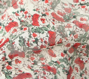 Detailed close-up of chiffon fabric with red rose floral print and mesh texture