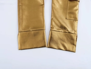 Détail du pantalon cargo doré en similicuir montrant l'ourlet et la texture de la poche