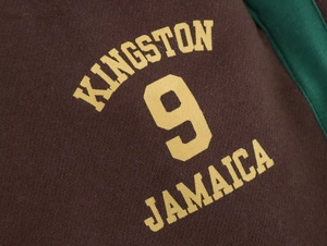 Dettaglio felpa con cappuccio marrone scuro con stampa Kingston 9 Jamaica gialla e riga