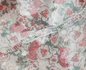 Detailed macro view of sheer mesh fabric with floral print and fine overlock stitching