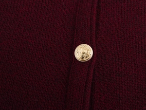 Macro shot of elegant gold embossed button on wine red knit cardigan sleeve