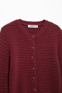 Detail view of burgundy knit cardigan featuring a round neck and textured crochet patterns