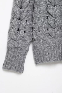 Détail de la maille torsadée grise et des poignets côtelés sur le pull à manches longues