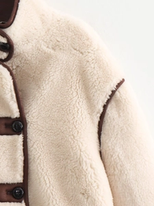 Detail of off-white faux shearling jacket with dark brown leather piping and black buttons