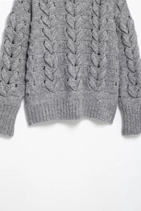 Vue détaillée du tricot à torsades et des poignets côtelés de ce pull gris élégant