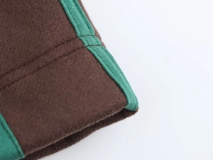 Dettaglio ravvicinato di tessuto pile marrone con bordi verde brillante e cuciture robuste