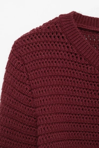Close-up of the ribbed round neck and hollow crochet texture on this wine red knit coat