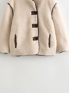 Detail of faux shearling jacket featuring brown piping, black buttons and side pockets