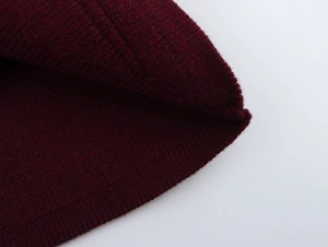 Close-up of deep red knit beanie showing ribbed hem and thick premium textured fabric
