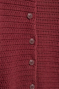 Detailed view of the textured hollow knit and matching buttons on a burgundy cardigan