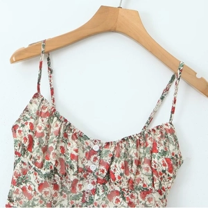Floral print strapless camisole with decorative buttons and delicate pleats hanging on hanger