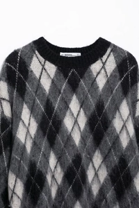 Detail von Rautenmuster-Strickpullover-Ausschnitt mit weicher Textur und gewebtem Etikett